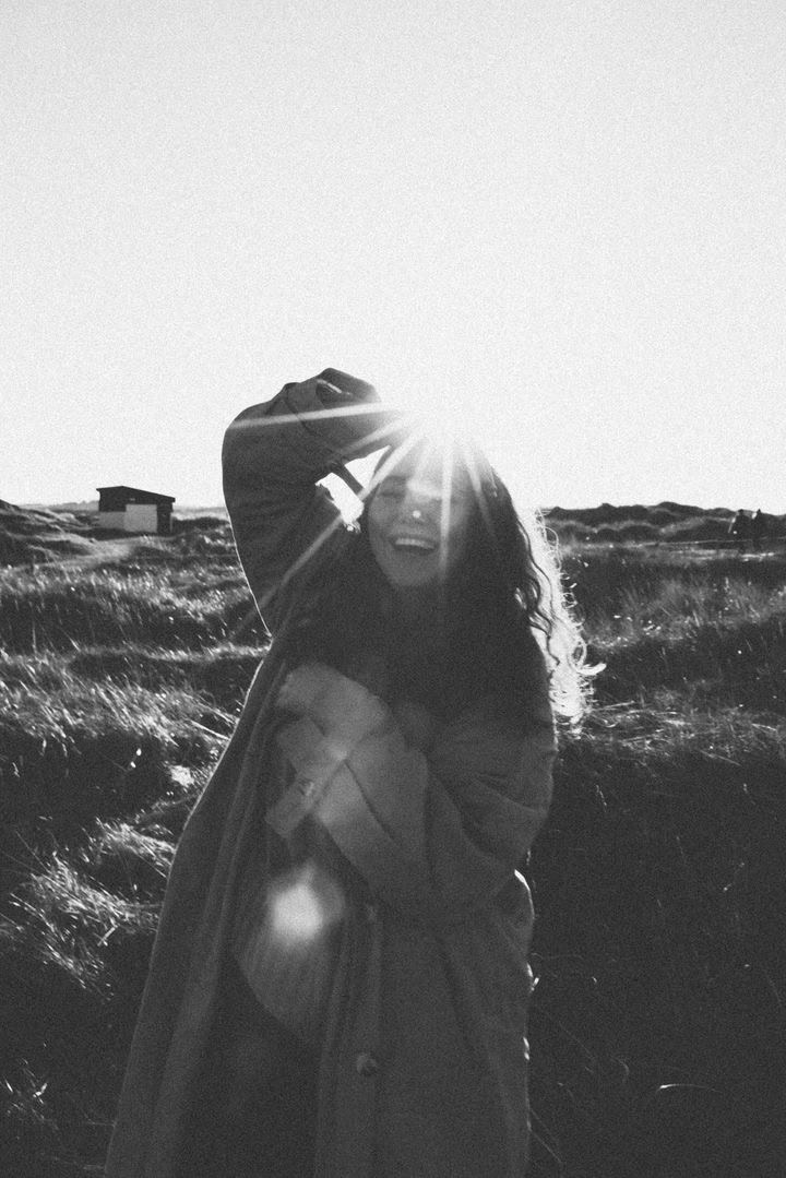 Bright smiling woman enjoying outdoor group program in natural landscape, sunlight, and fresh air.