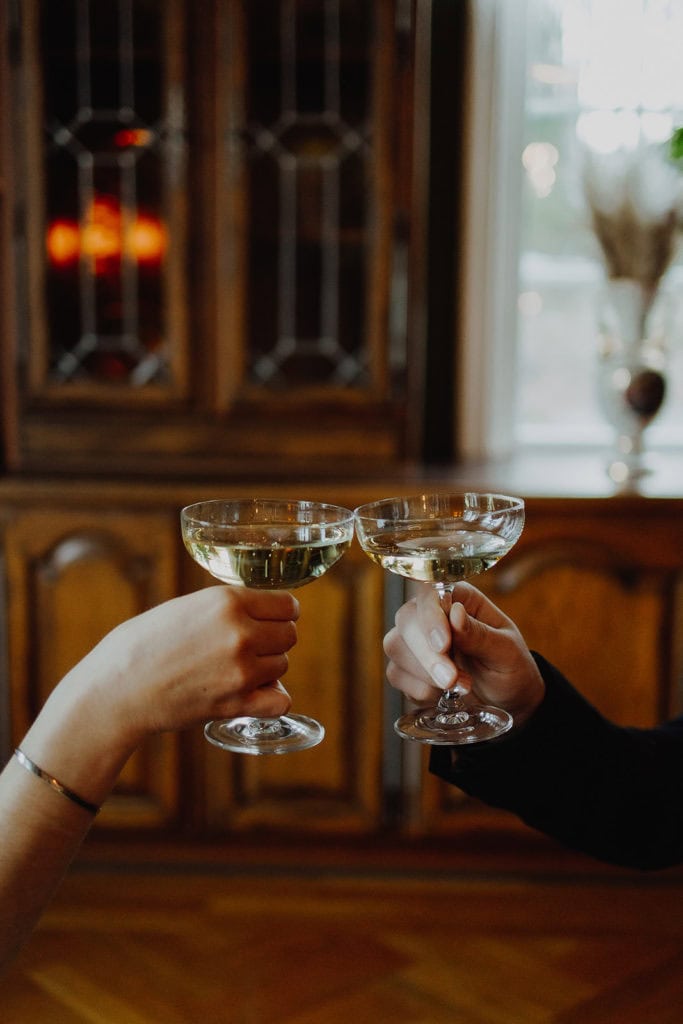 Elegant champagne glasses clinking during wedding celebration at a cozy venue.