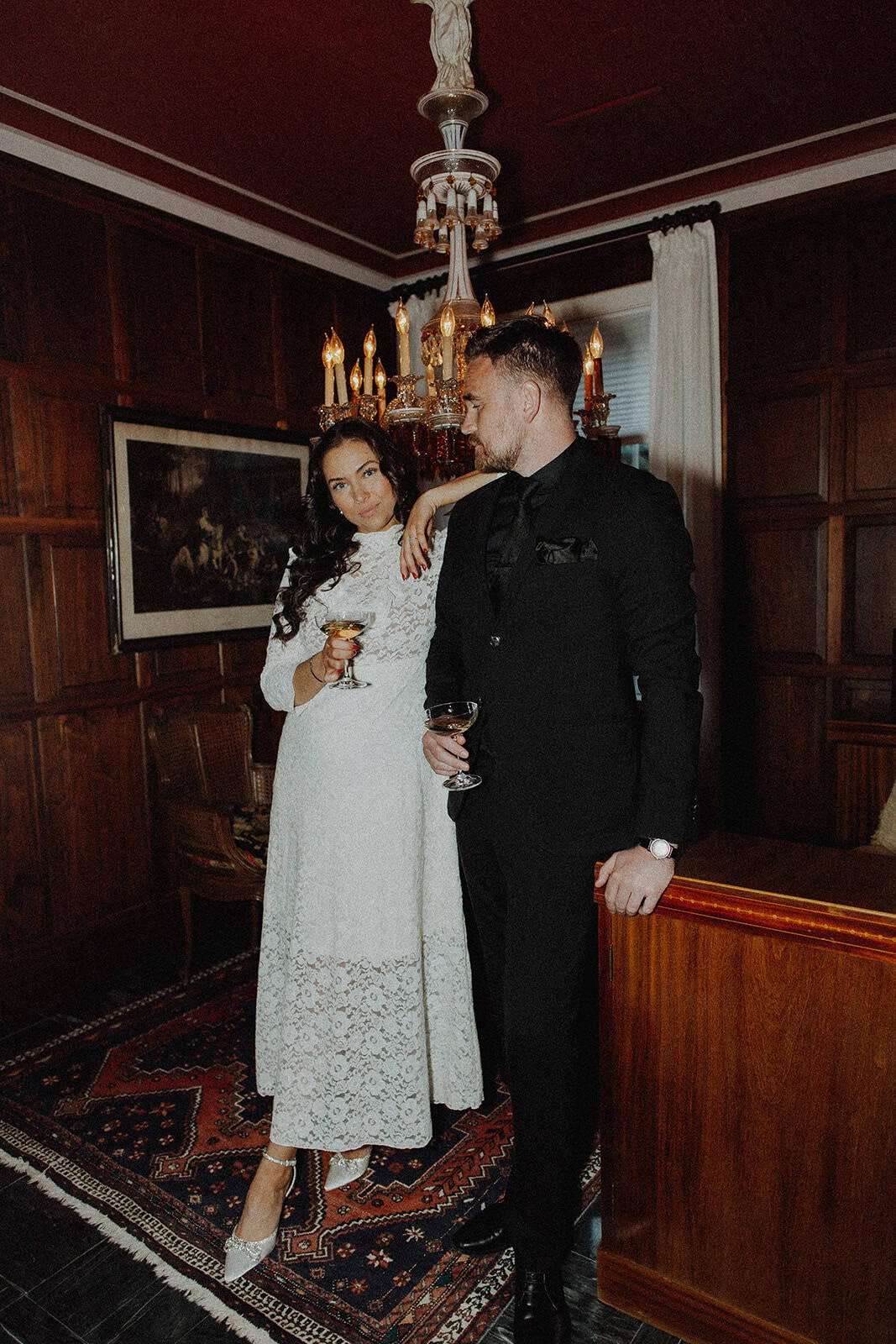 Elegant bride and groom at wedding workshop in a vintage, cozy room with chandelier.