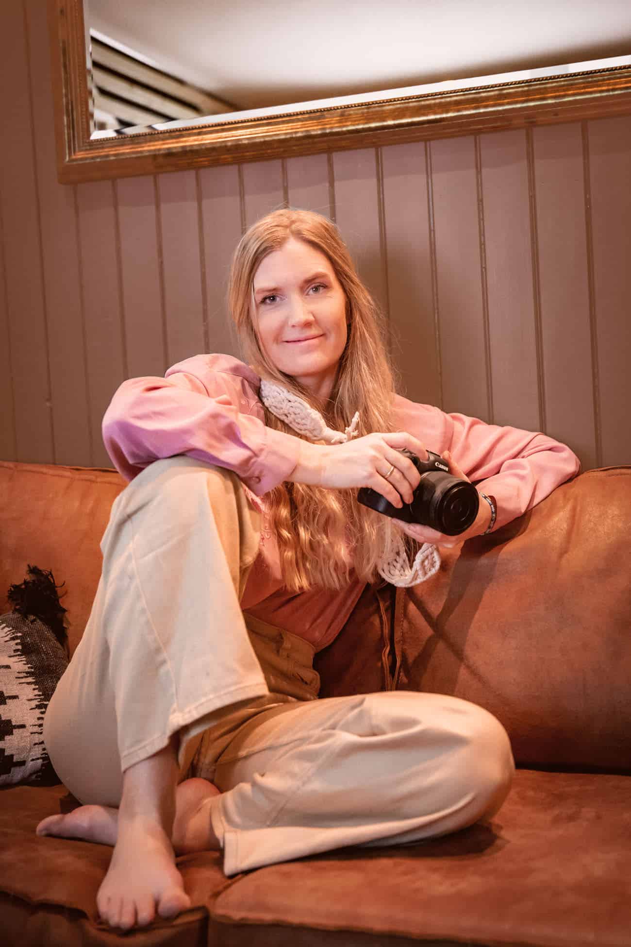 Elegant woman photographer sitting on a sofa with camera during wedding photography workshop.