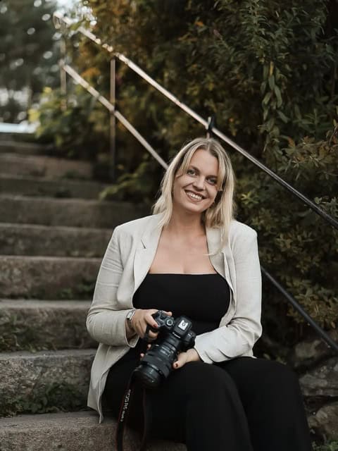 Woman holding camera sitting on outdoor steps
